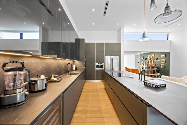 kitchen featuring a wealth of natural light, modern cabinets, freestanding refrigerator, and a sink
