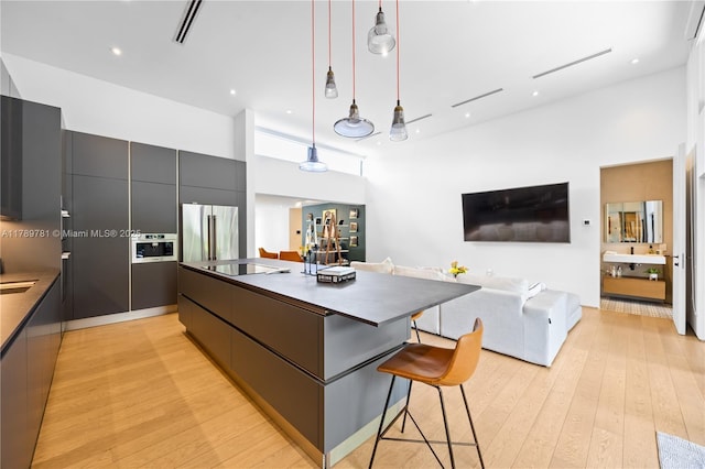 288 NE 117th St, Miami, FL 33161 - kitchen with modern cabinets, freestanding refrigerator, dark countertops, light wood finished floors, and a high ceiling