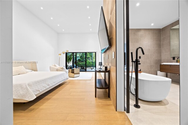 288 NE 117th St, Miami, FL 33161 - bedroom featuring recessed lighting, tile walls, a towering ceiling, and light wood finished floors