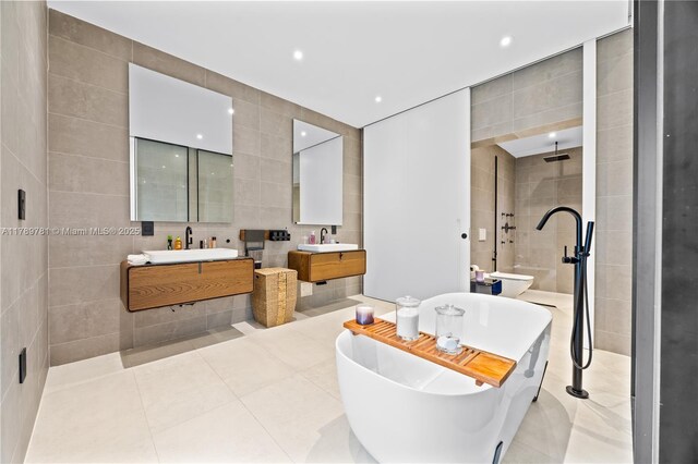 bathroom with tile walls, vanity, walk in shower, tile patterned flooring, and a soaking tub