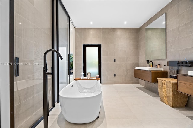 full bath with vanity, a soaking tub, tile patterned flooring, and tile walls
