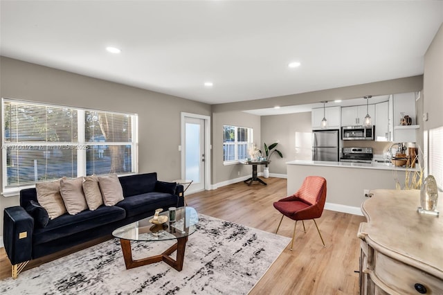 living room featuring light wood-style flooring, baseboards, and recessed lighting