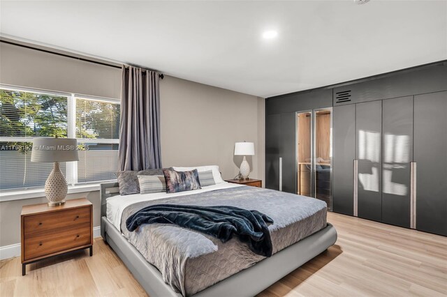 bedroom featuring light wood-type flooring, visible vents, and two closets