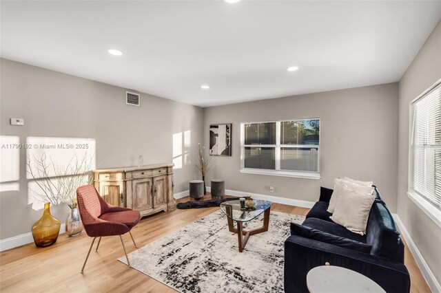 living area with a healthy amount of sunlight, wood finished floors, and visible vents