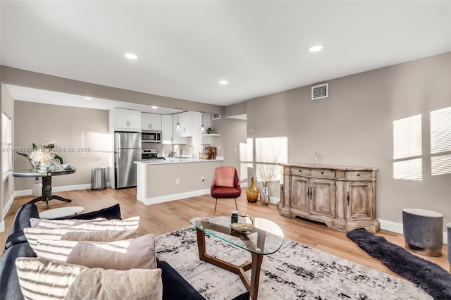 living area with recessed lighting, light wood-style flooring, visible vents, and baseboards