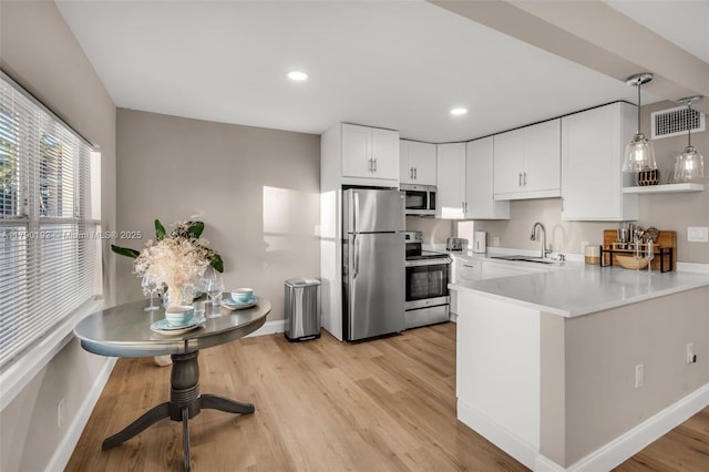 kitchen with stainless steel appliances, a sink, baseboards, visible vents, and light wood-style floors