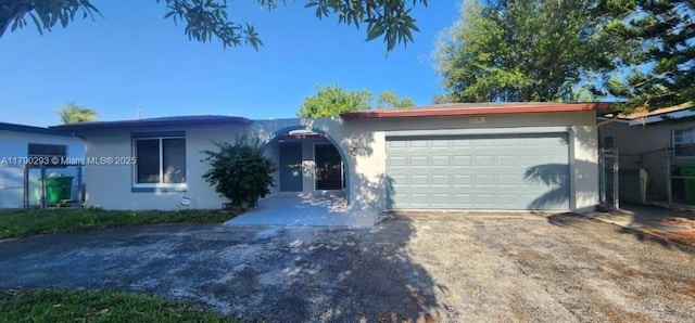 ranch-style house featuring stucco siding, driveway, french doors, and an attached garage