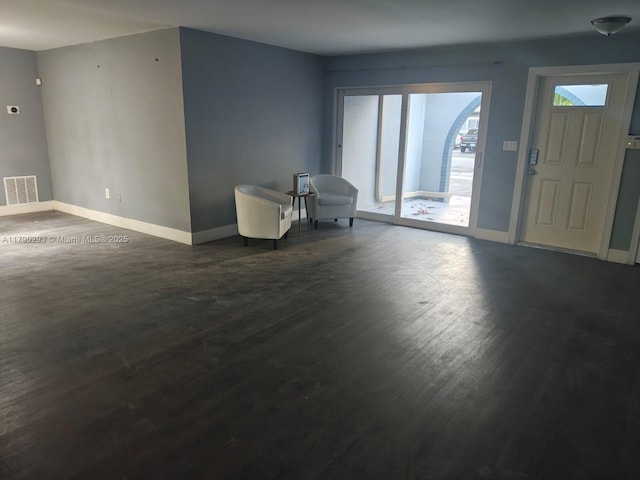 foyer entrance with dark wood finished floors, visible vents, and baseboards