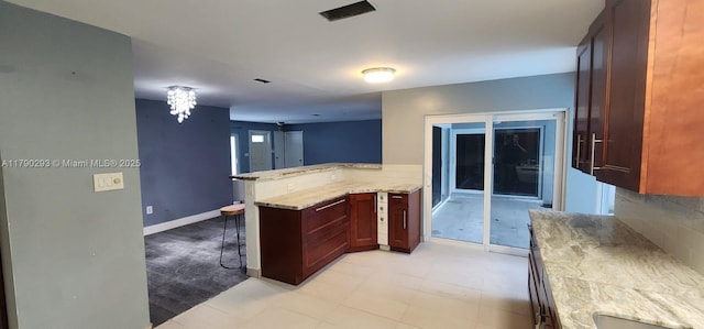 kitchen with a breakfast bar, baseboards, a peninsula, and light stone counters