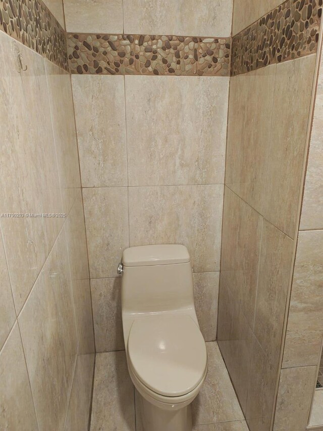 bathroom featuring tile walls and toilet