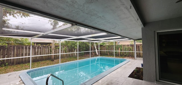 view of swimming pool featuring glass enclosure, a fenced in pool, and a fenced backyard
