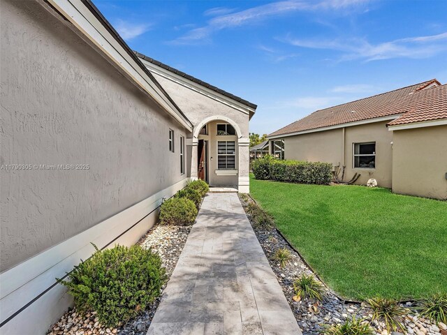 entrance to property featuring stucco siding and a yard