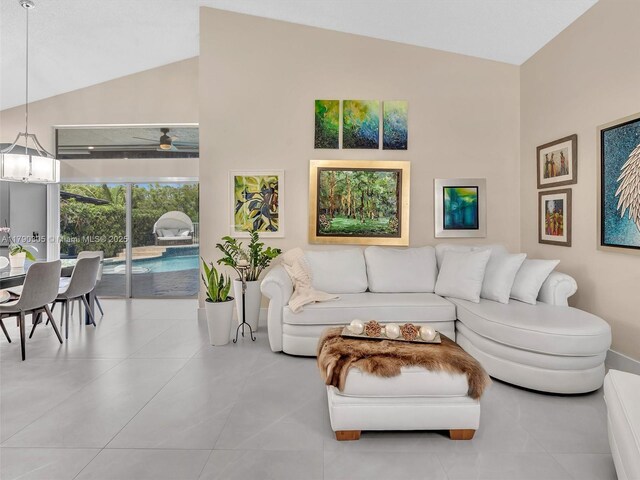 living room featuring vaulted ceiling, a ceiling fan, tile patterned flooring, and baseboards