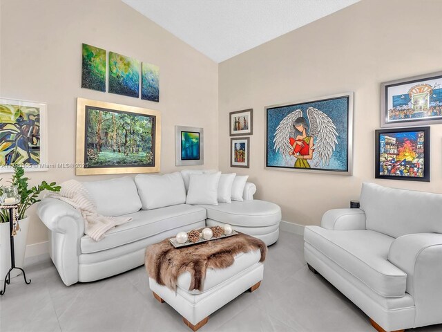 living area with tile patterned floors, vaulted ceiling, and baseboards