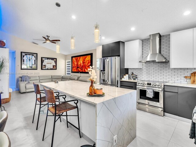 kitchen with light stone counters, stainless steel appliances, a breakfast bar, wall chimney range hood, and modern cabinets