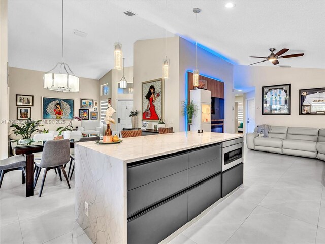 kitchen featuring stainless steel microwave, open floor plan, vaulted ceiling, ceiling fan with notable chandelier, and modern cabinets