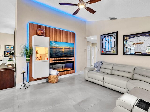 living room featuring vaulted ceiling, visible vents, baseboards, a glass covered fireplace, and ceiling fan