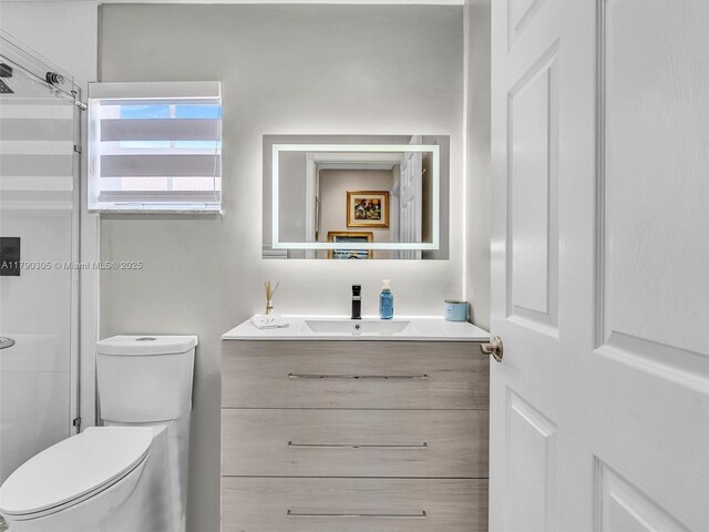 bathroom featuring toilet, vanity, and a shower