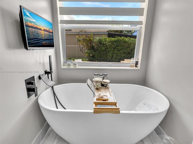 full bath featuring a freestanding tub and baseboards
