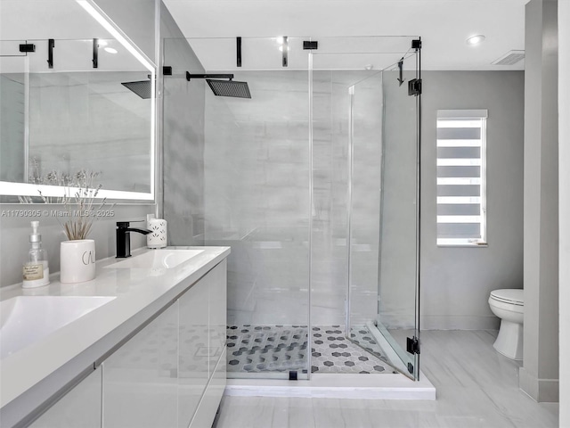 full bath with a shower stall, double vanity, visible vents, toilet, and a sink