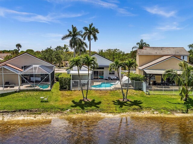 back of house with an outdoor pool, a lanai, a fenced backyard, and a lawn
