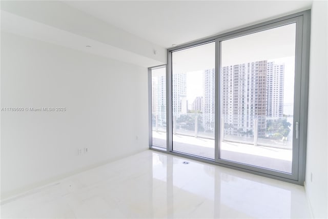 empty room with a wall of windows, tile patterned floors, and plenty of natural light