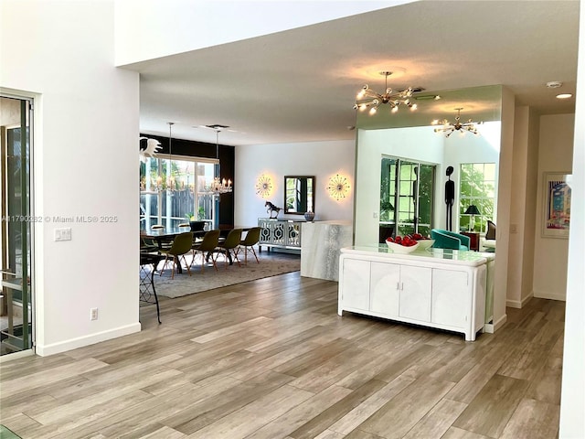 interior space with an inviting chandelier, baseboards, and light wood-style floors