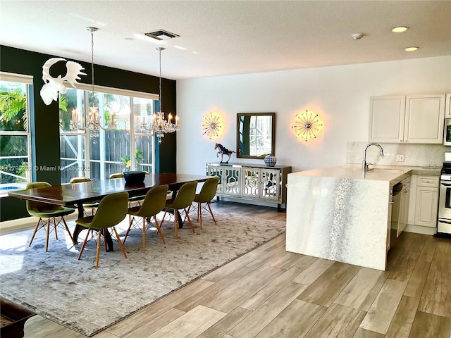 dining space with visible vents, wood finished floors, a notable chandelier, and a textured ceiling