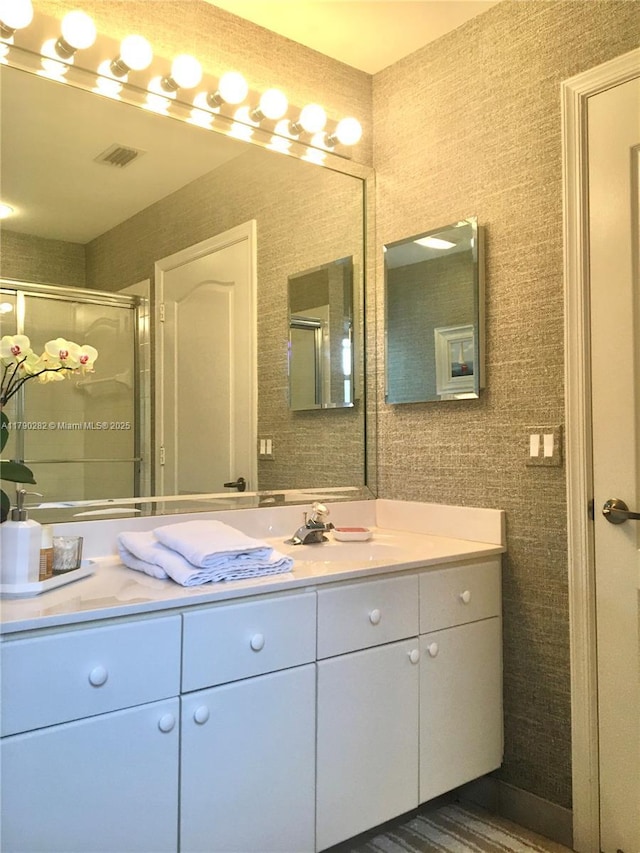 bathroom with visible vents, a shower stall, and vanity