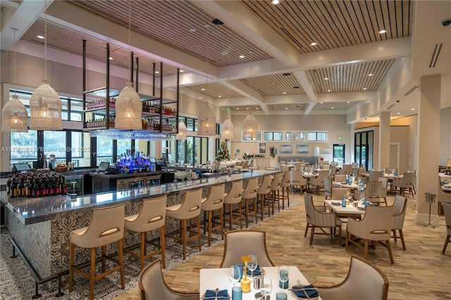 bar with beamed ceiling, coffered ceiling, a community bar, a towering ceiling, and wood finished floors