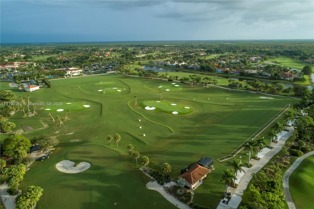 drone / aerial view featuring golf course view, a water view, and a residential view