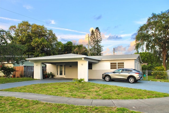 single story home featuring a front lawn, fence, an attached carport, and aphalt driveway