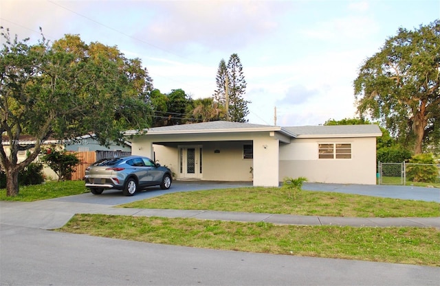 ranch-style house with a front lawn, driveway, an attached carport, and fence