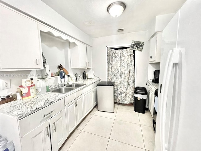 kitchen with white cabinetry, light countertops, freestanding refrigerator, and a sink