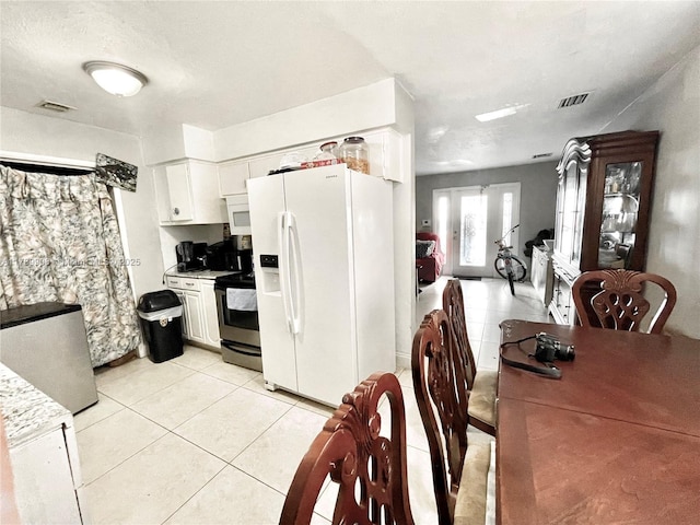 kitchen with white cabinets, visible vents, white appliances, and light tile patterned flooring