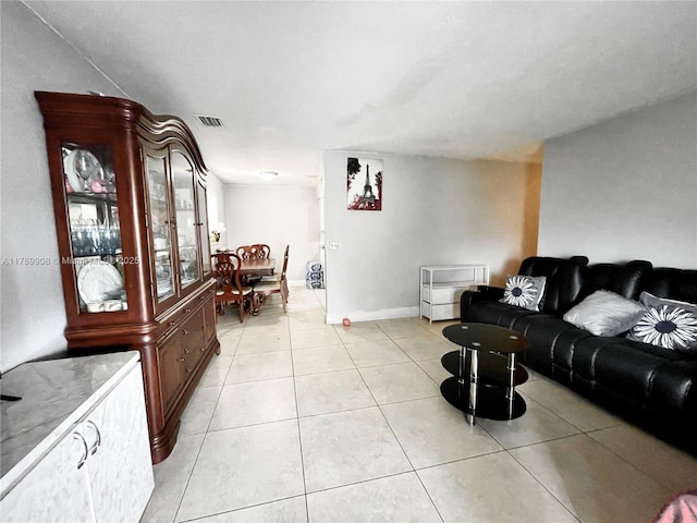 living room with light tile patterned floors, visible vents, and baseboards