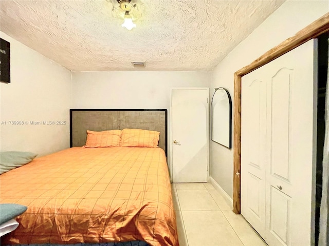 bedroom with visible vents, light tile patterned floors, and a textured ceiling