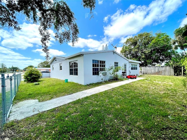 view of property exterior featuring stucco siding, fence, and a lawn