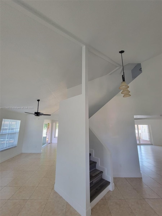 staircase with a ceiling fan, high vaulted ceiling, tile patterned floors, and baseboards