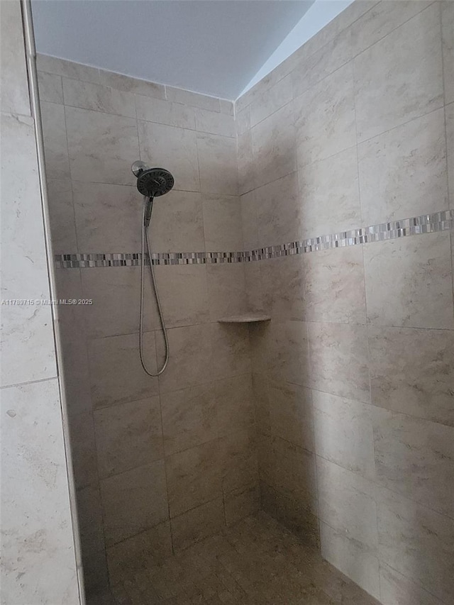 full bath featuring tiled shower and lofted ceiling
