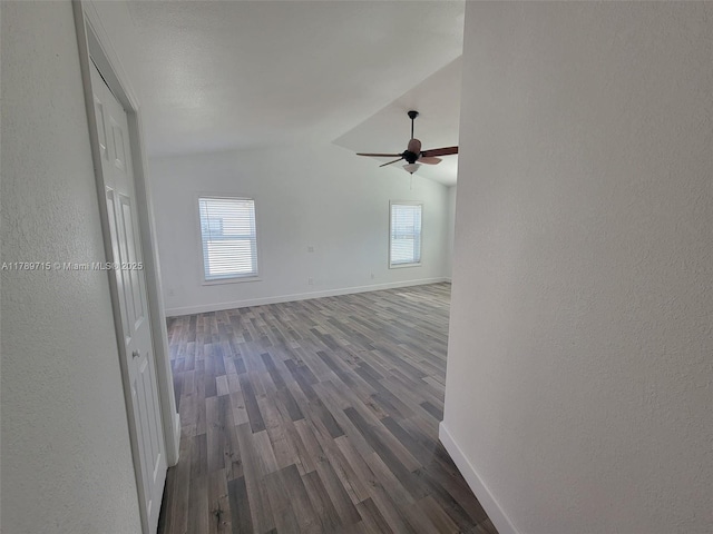 hallway with vaulted ceiling, a wealth of natural light, and baseboards