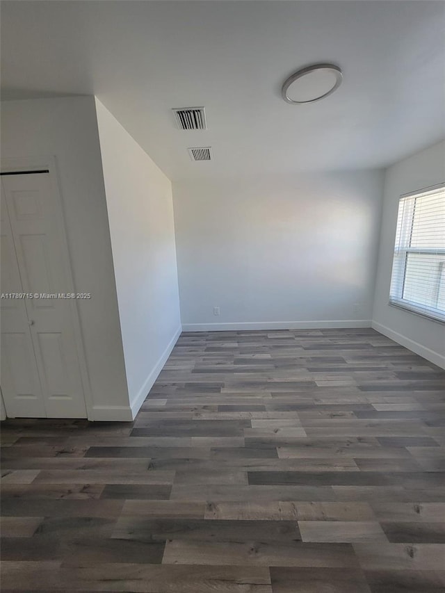 unfurnished room with wood finished floors, visible vents, and baseboards