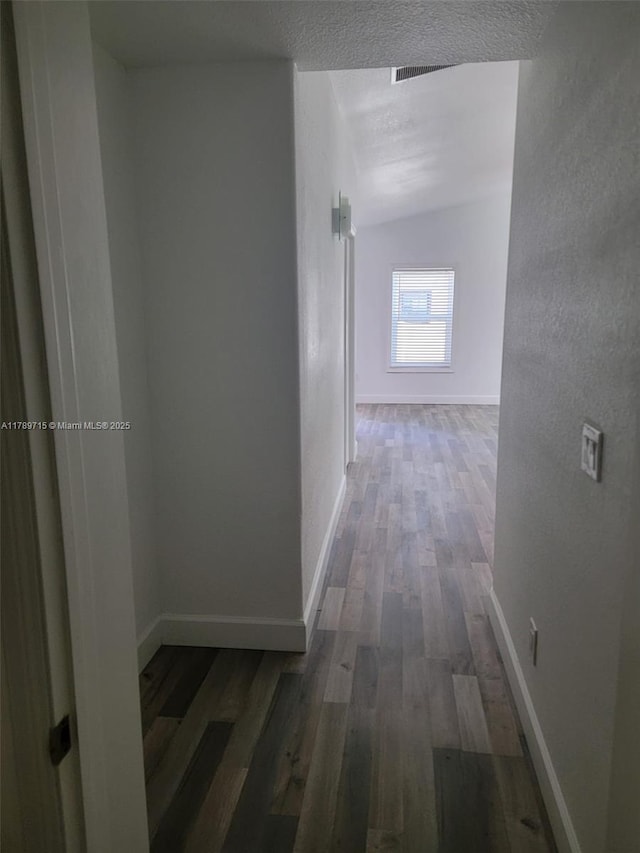 hall featuring baseboards, visible vents, and wood finished floors