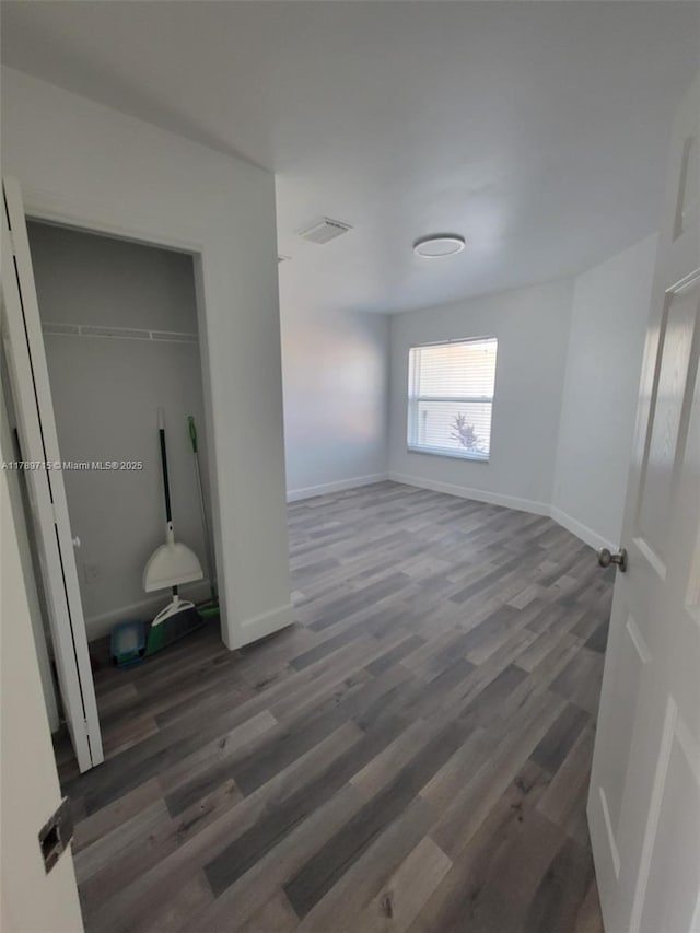 unfurnished bedroom with a closet, visible vents, wood finished floors, and baseboards