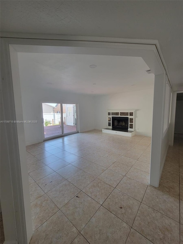 unfurnished room featuring light tile patterned floors and a fireplace with raised hearth