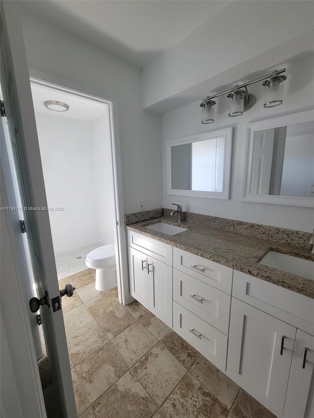 bathroom featuring double vanity, toilet, a shower stall, and a sink