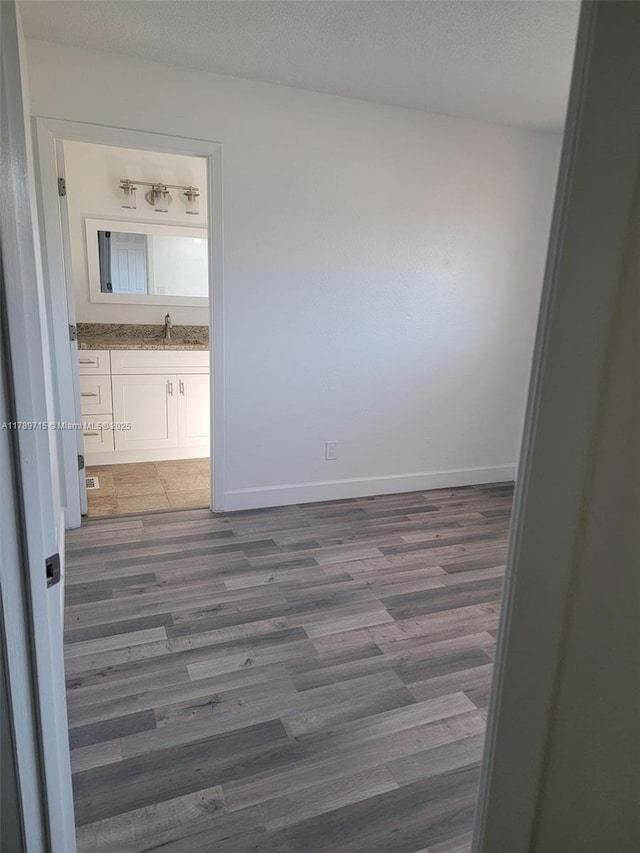 spare room with baseboards, wood finished floors, a textured ceiling, and a sink