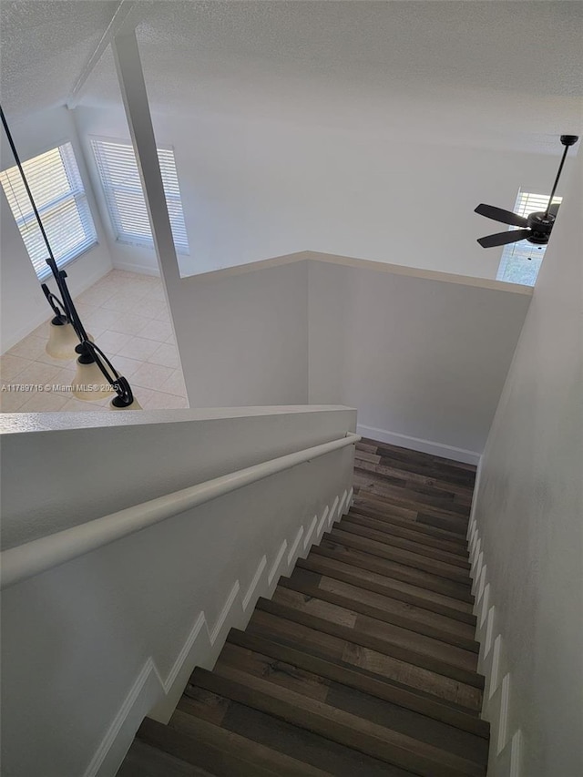 stairway featuring a textured ceiling and ceiling fan