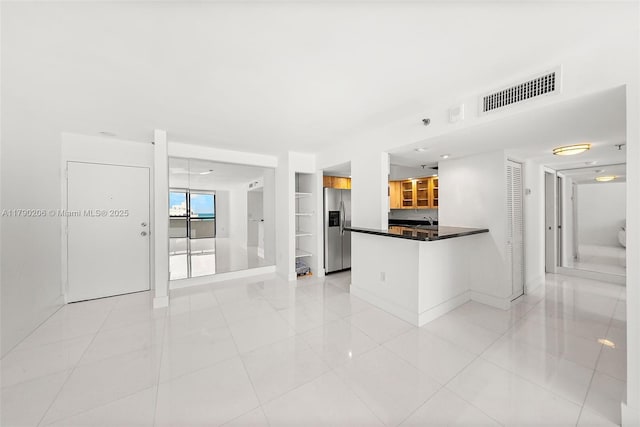 1775 Washington Ave Unit 11C, Miami Beach, FL 33139 - kitchen featuring stainless steel refrigerator with ice dispenser, a peninsula, dark countertops, baseboards, and light tile patterned flooring