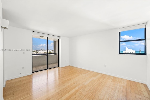 1775 Washington Ave Unit 11C, Miami Beach, FL 33139 - empty room with light wood finished floors, a wall of windows, and baseboards